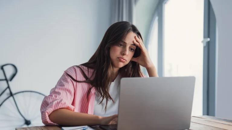 Femme découragée, la tête dans la main, devant son ordinateur portable qui ne reçoit plus ses mails